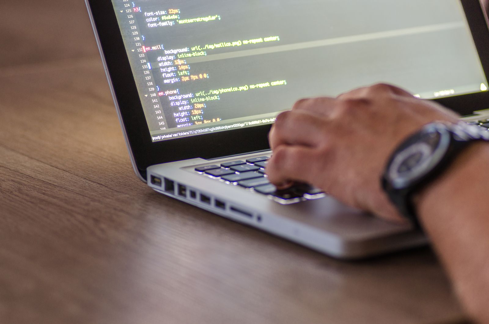 Main sur le clavier d'un ordinateur portable affichant du code, symbole de l'optimisation technique d'un site web