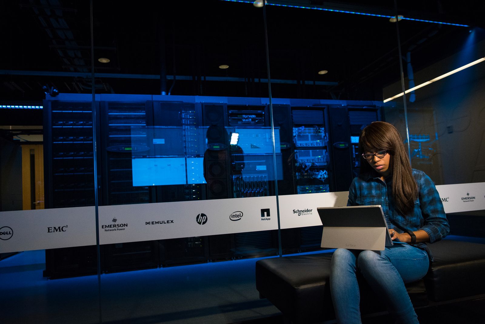 Développeuse travaillant sur un laptop devant une baie de serveurs, illustrant l'architecture back-end d'un CMS headless